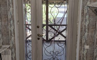 двустворчатая усиленная дверь в загородный дом со стеклом и коваными декоративными решетками